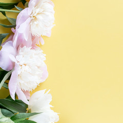 Pastel pink peony flowers bouquet on yellow background. Minimal floral flatlay concept.