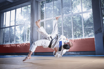 Two judo fighters showing technical skill while practicing martial arts in a fight club. The two...