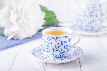 Elegant cup of green tea and white hydrangea on a white background. Free space