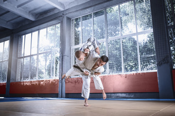 Two judo fighters showing technical skill while practicing martial arts in a fight club. The two...