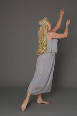 full length portrait of blonde girl wearing dress and crown. standing pose with back to the camera....