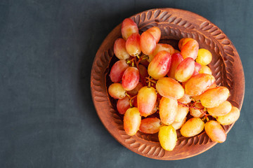 grape on brown plate on dark background with copy space