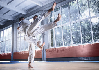 Two judo fighters showing technical skill while practicing martial arts in a fight club. The two fit men in uniform. fight, karate, training, arts, athlete, competition concept