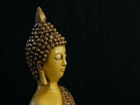 Image of Buddha's face from the side, over a dark background.