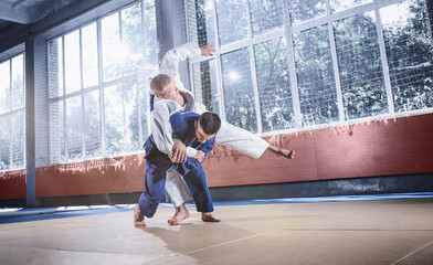 Two judo fighters showing technical skill while practicing martial arts in a fight club. The two...