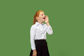 Do not miss. Young casual teen girl shouting. Shout. Crying emotional teenager screaming on green studio background. Female half-length portrait. Human emotions, facial expression concept. Trendy