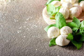 Mozarella small balls with fresh basil leaves on rustic background