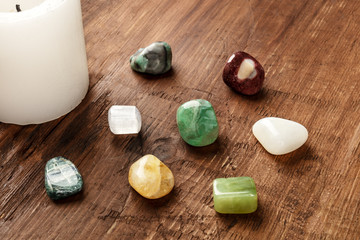 Semiprecious gemstones on a dark wooden background with candle and copy space