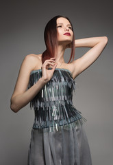 Fototapeta premium Fashion portrait of young woman posing in a beautiful grey dress. Professional make-up.