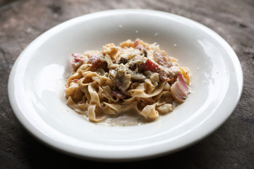 Pasta white sauce with bacon and mushroom on wood background in mystic light