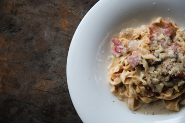 Pasta white sauce with bacon and mushroom on wood background in mystic light