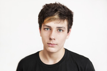 A handsome teenage boy with a sad face on a white background. Portrait of an angry teen in a black shirt