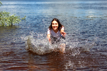 a beautiful girl standing in the river in wet clothes enjoys vacations