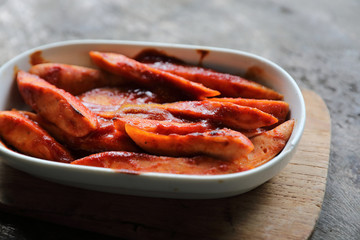 Traditional German currywurst pieces of sausage with curry sauce on wood background
