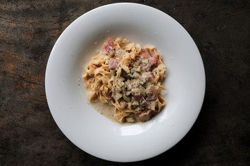 Pasta white sauce with bacon and mushroom on wood background in mystic light