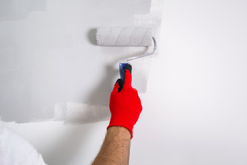 Painter hand painting a wall with paint roller