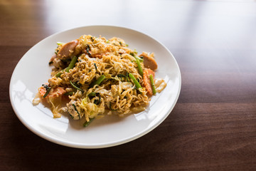 noodle fried with vegetables on wooden table near windows