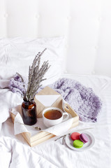 Morning breakfast in bed wooden tray with a cup of tea, sweet colorful french macaroons, love letter, bouquet of lavender. Top view Morning at Hotel or at home. Background Concept Cozy morning