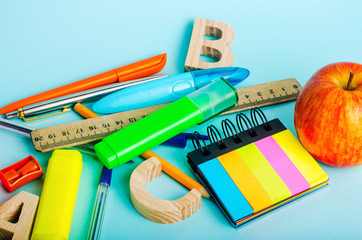 letters, apple, ruler, pens, scissors, colored markers, pencils, sticky stickers, sharpener on the...