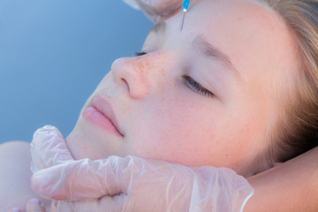 Portrait of teenage girl doing botox injection of hyaluronic acid in forehead skin close up, concept of youth and beauty