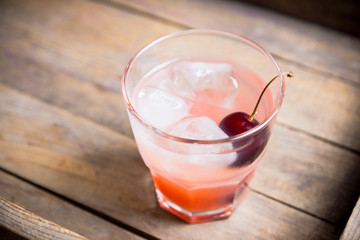 Old fashioned cocktail with cherry. Selective focus.