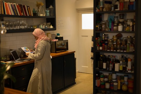 Muslim woman looking at the printout in kitchen