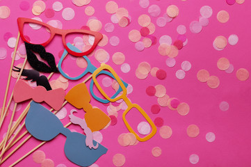 Photo booth props glasses, mustache, lips on a pink background flat lay. Birthday parties and weddings.