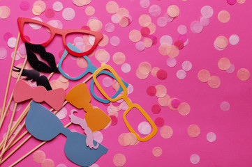 Photo booth props glasses, mustache, lips on a pink background flat lay. Birthday parties and...