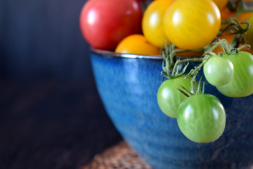 Naklejka na ściany i meble Close-up of cherry tomatoes of three colours in a blue bowl. Copy space