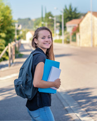 Back to school. Student girl holding books and carry school bag while walking to school. Urban background.