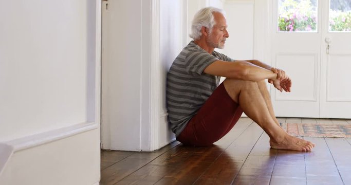 Senior man sitting on floor at home 4k