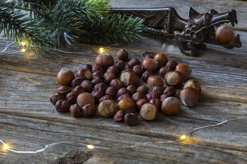 on a wooden table lie hazelnuts, a pine branch, a garland with lights and a device for picking nuts - winter background 