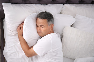Man sleeping on comfortable pillow in bed at home, top view
