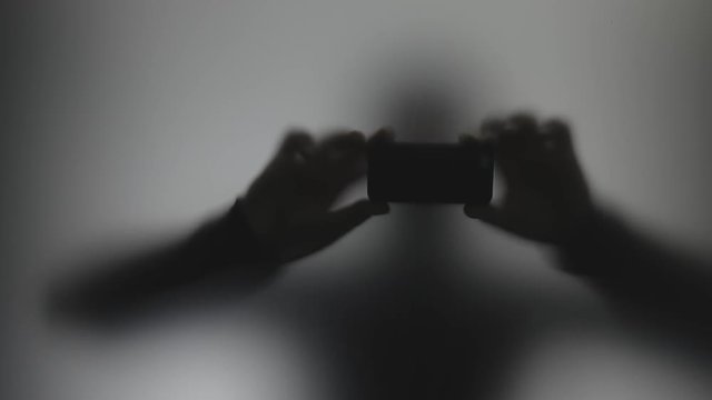 Anonymous shadow stalker shooting video on phone