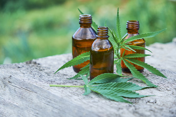 hemp leaves on wooden background, seeds, cannabis oil extracts in jars.