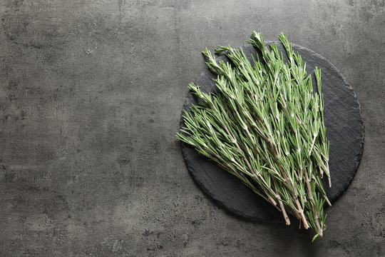 Slate plate with fresh rosemary twigs on table, top view