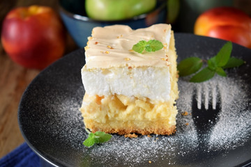 Piece of meringue pie with fruits and cottage cheese on a dark plate