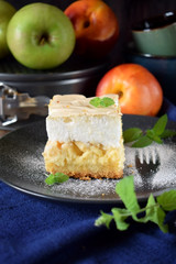 Piece of meringue pie with fruits and cottage cheese on a dark plate