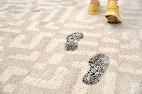 Person In Dirty Shoes Leaving Muddy Footprints On Carpet