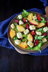 Fruit salad with arugula, plums, nectarines and soft cheese on a plate