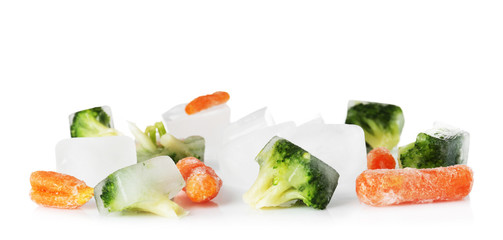 Frozen vegetables and ice cubes on white background