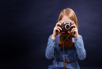 Blond hair girl take a picture with vintage photo camera in leather case