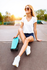 Portrait of a beautiful girl in the Park with a skate, summer mood