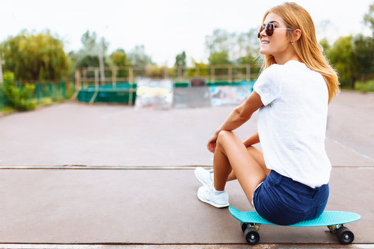 portrait of a beautiful girl, with a skate, in a skate Park, summer day