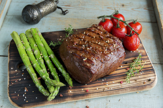 beef steak grilled with asparagus tomatoes spice on a wooden surface