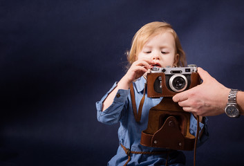 little girl try to take a picture with vintage photo camera and father hand helps her