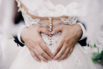 wedding photo of wedding rings on the groom's hands. heart