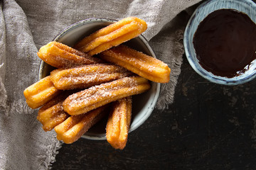 Traditional Mexican dessert churros with chocolate sauce. Dark background