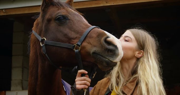 Woman kissing horse in stable 4k
