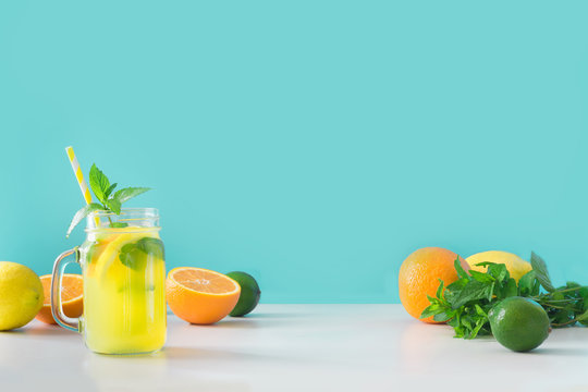 Lemonade in mason jar with lemon and mint on blue. Copy space.